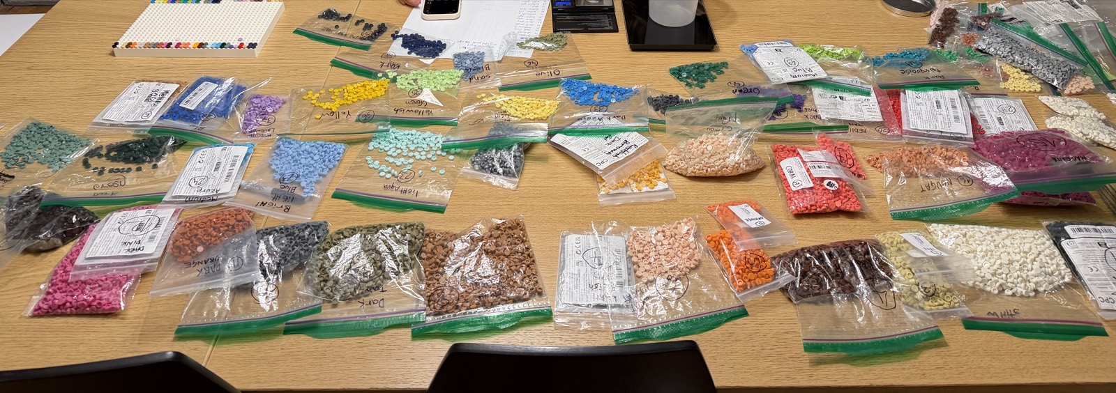 Una mesa cubierta de bolsas transparentes de dots de colores, cada una etiquetada a mano con su color y su cantidad